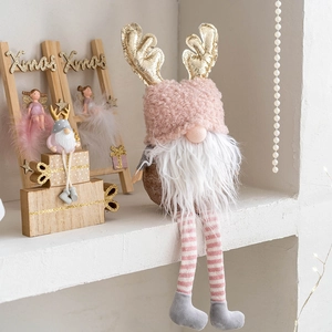 Pink Christmas gnome plush with gold antlers sitting on a shelf with Xmas decor