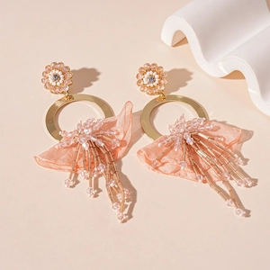 Macro detail of peach lace fringe and sparkling rhinestone flower on golden round earrings