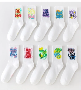 Close-up of 10 white cotton crew socks featuring vibrant graffiti slogans and knit texture