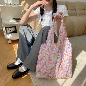 Dettaglio borsa shopper con stampa a tulipani, etichetta logo bianca e spalline larghe