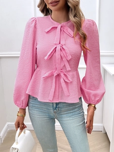 Close-up of pink checkered puff-sleeve top with decorative bows and seersucker fabric detail