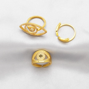 Detailed view of three gold evil eye rings with sparkling crystals on white silk