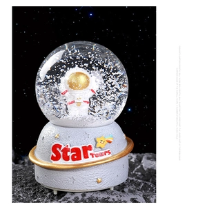 Detailed macro view of an astronaut crystal ball music box with textured moon base