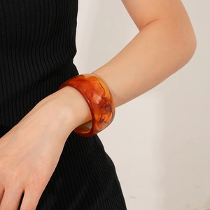 Macro detail of a wide vintage amber resin bangle featuring polished tortoise patterns