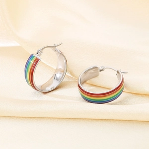 Makro-Detail von Regenbogen-Creolen auf elegantem Seidenhintergrund-Stoff