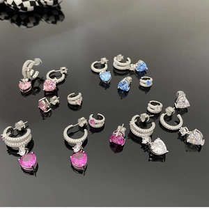 Vue macro de boucles d'oreilles argentées avec zircons cœur sur fond miroir noir brillant
