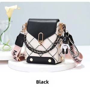 Detail of black and white quilted crossbody bucket bag with chain and bear charm