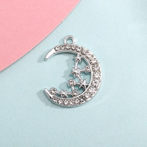 Silver crescent moon pendant with rhinestones and star detail on pink and blue background
