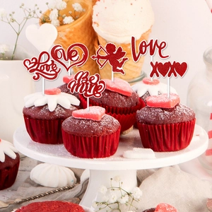 Close-up of red glitter heart cake toppers with Love and XOXO text on velvet cupcakes