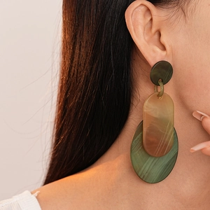 Gros plan de boucles d'oreilles géométriques en résine ambre et vert émeraude marbré