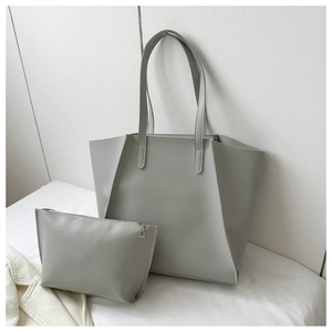 Detail of grey minimalist tote bag and matching zippered inner pouch on white bedding