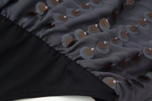 Close-up of grey pleated fabric with tiered brown sequins and black elastic strap detail