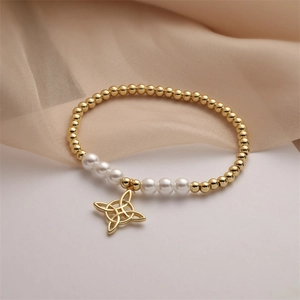 Detail of gold beaded bracelet featuring a Celtic knot charm and elegant pearls