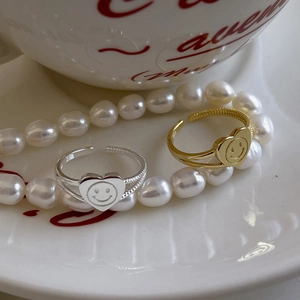 Detail of 925 silver heart rings with smiling face and twisted texture in warm lighting
