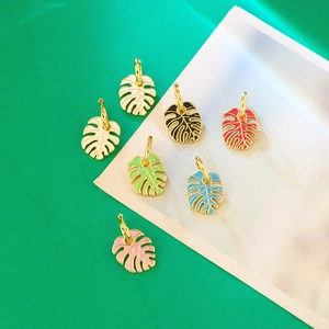 Detailed view of colorful monstera leaf earrings with gold frames and oil drip finish