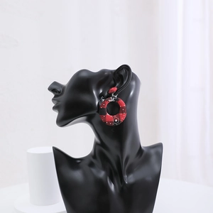 Detail of red and black buffalo plaid round earrings with snowflake on a black model bust