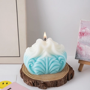 Close-up of lit blue and white gradient candle with wave texture on wood base