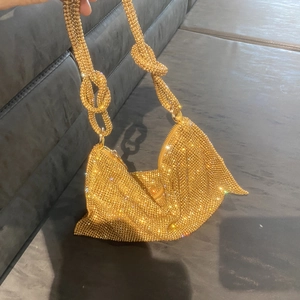 Detail view of a gold rhinestone hobo bag featuring unique double knot shoulder strap design