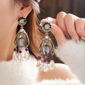 Detail of vintage gold tassel earrings with dark pearl stones and purple crystal drops