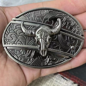 Macro shot of silver belt buckle with bull skull relief and western floral engraving