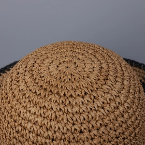 Top view of a wide brim straw sun hat with handwoven texture and black edge detail