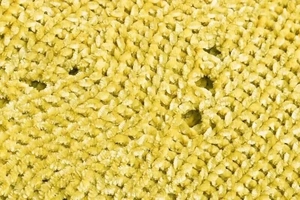 Detailed macro shot of yellow mustard chenille fabric with rich tufted knit texture