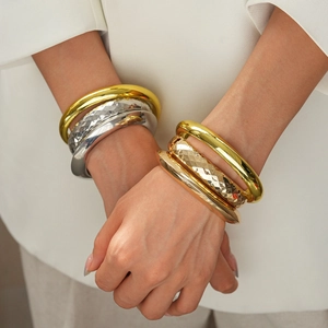 Polished geometric metal bangles in gold, silver and rose gold finishes on model's wrist