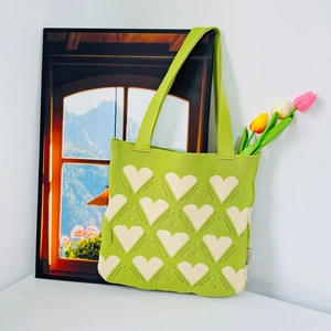 Green knitted heart pattern tote bag with tulip flowers in a fresh aesthetic setting