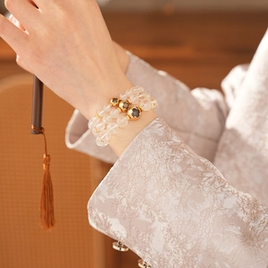 Detailed view of beaded bracelets with white crystals, gold accents, and a floral charm