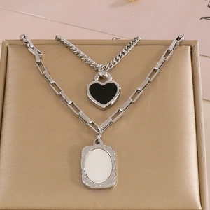 Double-layered silver necklace with heart and oval pendants on metallic stand