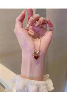 Close-up of 18k gold plated necklace featuring a red heart pendant worn by a model