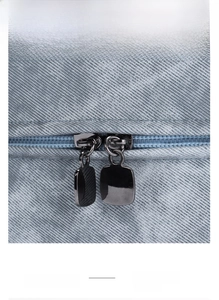 Detail of smooth double black metal zippers on grey twill fabric travel wash bag