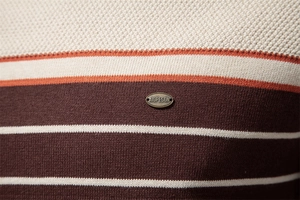 Macro shot of striped knit sweater showing texture and brand metal logo detail