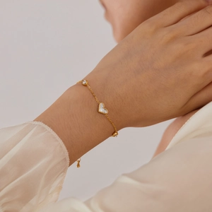Elegant gold titanium steel bracelet featuring a white shell heart and sparkling zircon stones