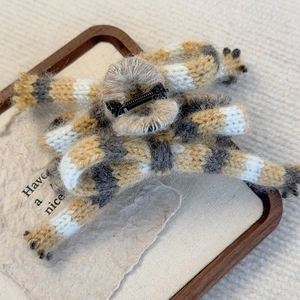Macro view of plush striped knitted hair claw clip on a rustic wooden tray decoration