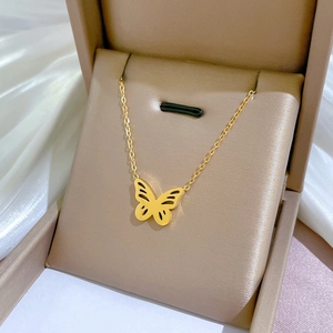 Collana con ciondolo a farfalla dorata in scatola su sfondo di seta bianca