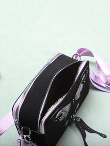 Detail of black and purple crossbody bag with butterfly pattern and metal rivets