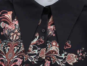 Detailed close-up of ethnic print collar and buttons on black long-sleeve blouse