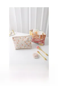 Detail of floral and striped corduroy cosmetic bags on white surface with curtains