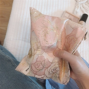 Detail of elegant pink rose jacquard fabric and metal zipper on the small makeup bag