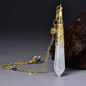 Macro shot of hexagonal selenite crystal pendulum with gold filigree metal cap detail