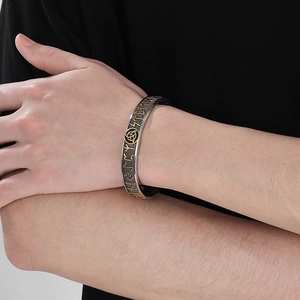 Macro detail of Nordic Viking runes and gold trinity symbol on vintage cuff bracelet
