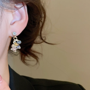 Close-up of golden horse pendant earring with colorful rhinestones worn by a model