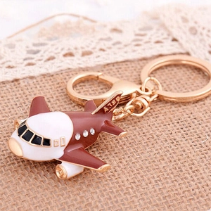 Macro shot of a red and white metal airplane keychain with A380 text on a linen background