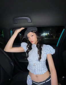 Detail of blue and white striped puff sleeve top with V-neckline and waist pleats