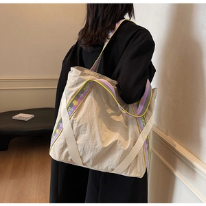 Détail du grand sac cabas en nylon crème avec bandoulière rayée sur le mannequin