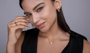 Close-up of elegant gold plated jewelry set featuring a necklace, hoop earrings and ring