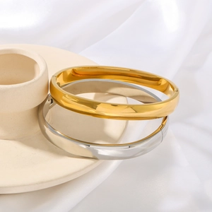 Polished gold and silver minimalist geometric bangle set on an elegant ceramic base