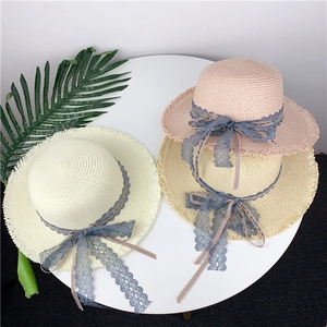 Detail view of woven straw sun hats with lace ribbons and fringed edges in three colors