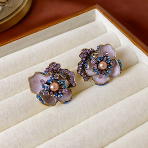 Detail of vintage enamel flower earrings with pearls and rhinestones in a jewelry box